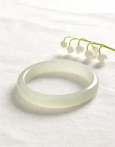Elegant close-up of a translucent pale green cat's eye bangle on textured white fabric