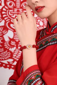 Red agate beaded bracelet with white agate peace buckle and gold zodiac charm on model's wrist