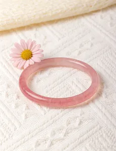 Elegant pink strawberry quartz bangle on white knitted background with a flower