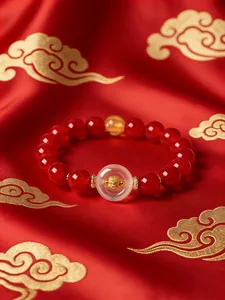 Detail of red agate beaded bracelet with white agate safety buckle and gold charm.