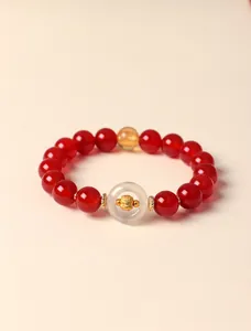 Macro detail of red agate beaded bracelet with white agate donut and golden zodiac charm