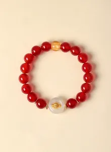 Close-up of red agate beaded bracelet with white agate charm and gold zodiac monkey.