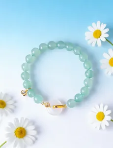 Close-up of green bead bracelet with white agate Ping An Kou pendant and gold charms
