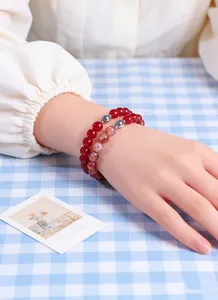 Close-up of natural red crystal beaded bracelets stacked on model wrist