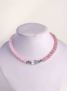 Detail of pink and clear natural crystal beaded necklace on a white display stand