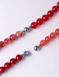 Close-up detail of natural red crystal beads featuring a round silver magnetic clasp