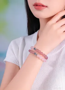 Detailed view of pink rose quartz and strawberry crystal beaded bracelets on a wrist.