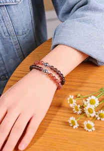 Detailed macro view of natural crystal beaded bracelets with strawberry quartz on wrist.