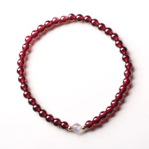 Makrodetail von 4mm Granatperlen und schillerndem Mondstein mit 14k Goldakzenten auf Armband
