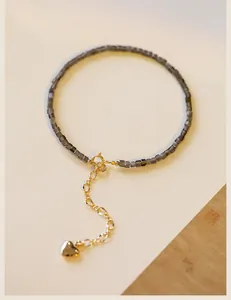 Close-up detail of a delicate 2mm silver obsidian bead bracelet with a gold heart charm
