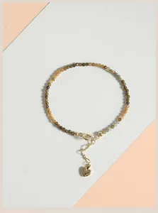 Detailed view of 2mm yellow tourmaline beaded bracelet with golden heart charm.