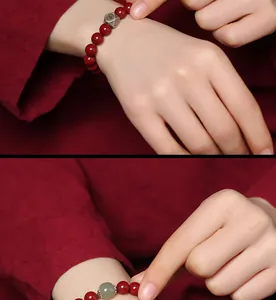 Detailed macro shot of a red cinnabar bead bracelet featuring a green Hetian jade and silver bead