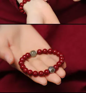 Close-up detail of a red cinnabar bead bracelet with jade and silver accents