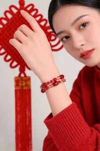 Detailansicht eines Armbands aus rotem Achat und gelbem Kristall an einem Model in Rot
