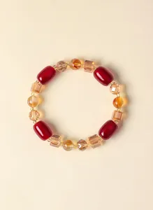 Detailansicht von roten Achattrommelperlen und gelben Kristallperlen in einem Armband-Design.