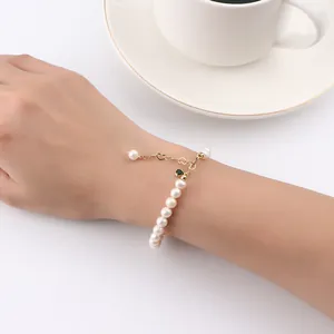 Close-up detail of a natural freshwater pearl bracelet with gold heart chain on wrist