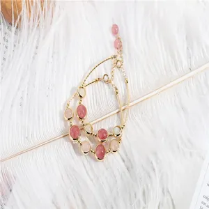 Close-up detail of 14k gold plated strawberry quartz beaded bracelets on soft feather
