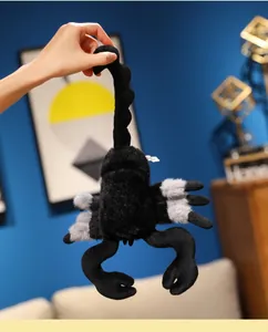 Macro shot of a soft black and gray plush scorpion toy held by a hand to show size.