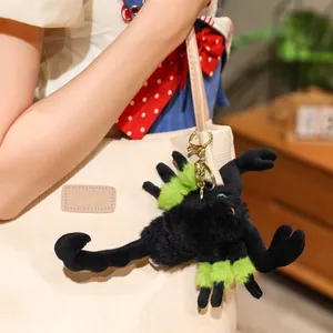 Unique stylized black and green plush scorpion keychain charm hanging on a beige tote bag
