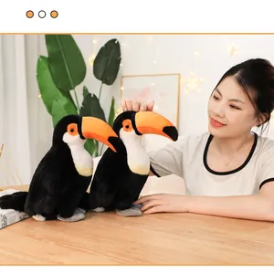 Close-up of two realistic toucan plush toys on a wooden table with a model
