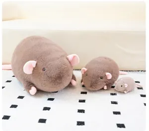 Close-up of three realistic brown mouse plush toys in different sizes on a soft white carpet