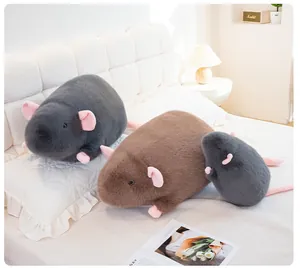 Three realistic rat plush toy dolls of various sizes displayed on a cozy white bed