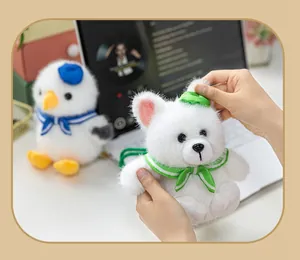 Detail view of a soft white plush fox keychain held in hands with a seagull friend.