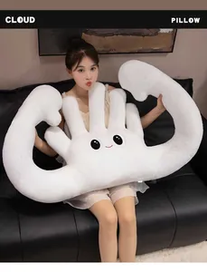 Weiches weißes handförmiges Plüschkissen, gehalten von einem Model auf dem Sofa.