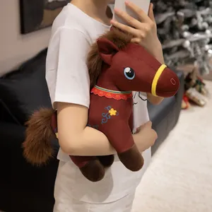 Cute brown plush horse toy with decorative embroidery, held in a cozy home setting