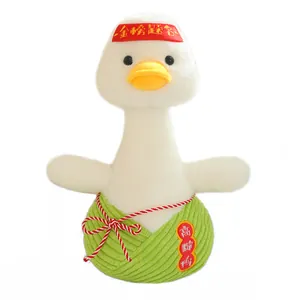 Detail view of cute white plush duck doll featuring a red headband and green textured wrap