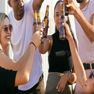 Blijde vrienden proosten met bierflesjes op een zonnig feestje in de buitenlucht