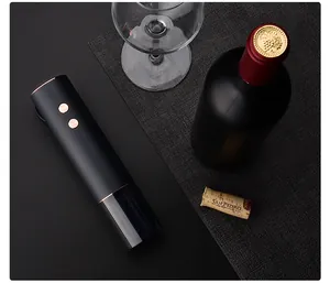 Overhead detail shot of a sleek matte black electric wine opener with wine bottle and glass