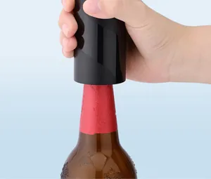 Dichtbij van een hand die een zwarte automatische bieropener op een fles gebruikt