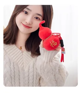Close-up of a model holding a red plush gourd keychain with embroidered Fu character detail