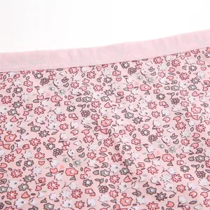 Gros plan du tissu de culotte en coton fleuri avec détail de taille élastique rose.