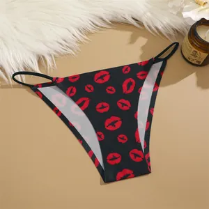 Close-up of black seamless panties with red kiss print pattern on beige background.