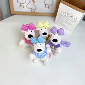 Close-up of four plush West Highland dog bag charms with colorful bows and sweaters.