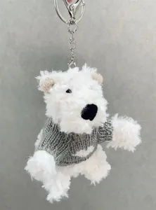 Vue détaillée d'un porte-clés chien en peluche blanc avec un pull en tricot gris