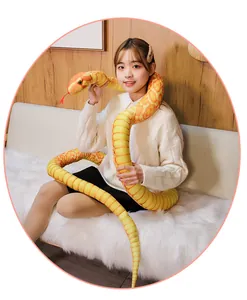 Realistic yellow and orange giant snake plush toy held by a model in a home setting