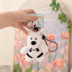 Primo piano di un simpatico portachiavi in peluche di cane bianco in una mano.