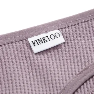 Dettaglio del tessuto in cotone a nido d'ape malva e etichetta FINETOO su perizoma da donna