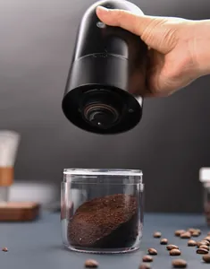 Détail du mini moulin à café électrique montrant le café moulu dans le bac transparent