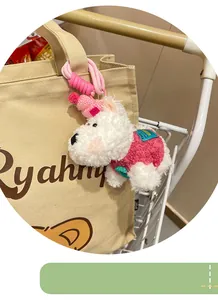 Close-up detail of a cute white plush Westie dog keychain hanging on a beige canvas bag