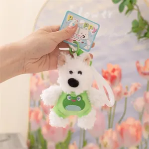 Primo piano di un simpatico portachiavi a forma di cane di peluche bianco con abito da rana.