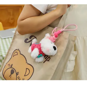 Cute plush Westie dog keychain charm hanging on a stylish canvas tote bag detail view
