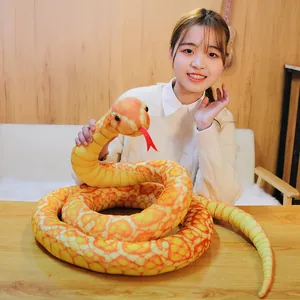 Close-up detail of a realistic yellow python plush toy with orange patterns and red tongue