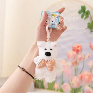Primo piano di un simpatico portachiavi a forma di cane di peluche bianco con fiocco