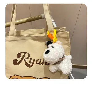 Close-up of fluffy Westie plush dog keychain hanging on a beige tote bag