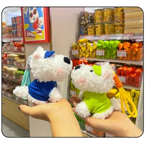 Close-up of two scruffy Westie plush dog keychains in blue and green outfits