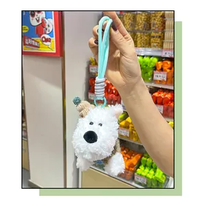 Detail of handheld white fluffy Westie dog plush keychain charm in a retail store